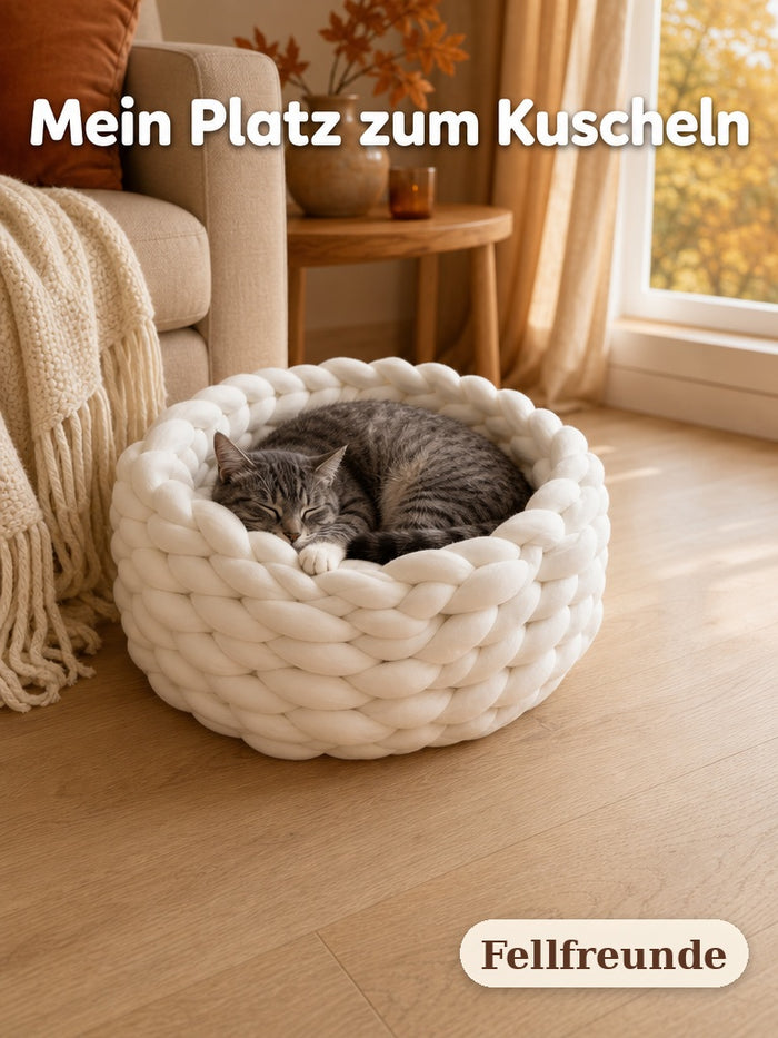 Graugetigerte Katze schläft eingerollt im weißen Katzenbett